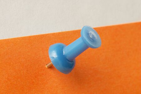 Blue pushpin over orange sticker note macro shot backgroundの写真素材