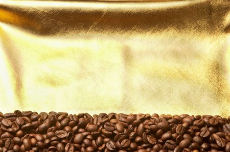 Roasted coffee grains background macro shot over golden clothの写真素材