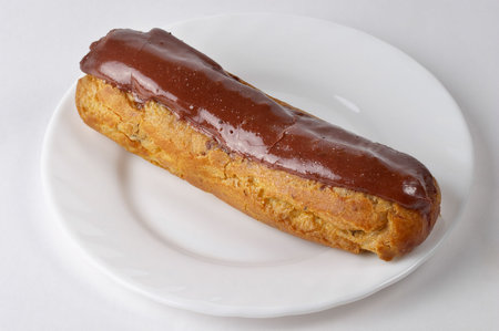 Glazed eclair macro shot over grey gradient background