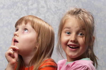 Two little girlfriends thinking and smiling one portraitの写真素材