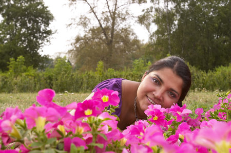 Young smiling indian woman lying on the grass in the parkの写真素材