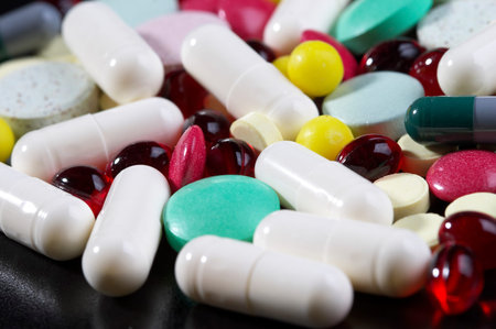 Colored glossy rounded multi vitamin pills macro shot over black background