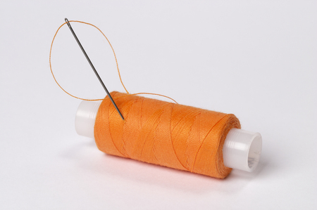 orange thread with needle over white backgroundの写真素材