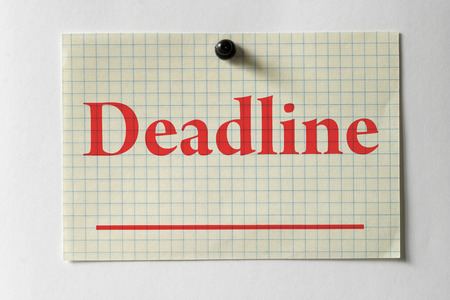 White checked note "Deadline" with a black push-pin over white paperの写真素材