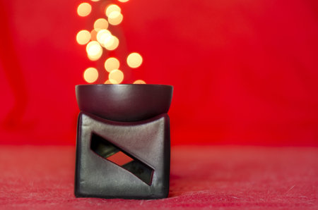 ceramics decorative candle holder on red background with lights coming out of itの写真素材