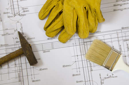 building plans with hammer, paint brush and working gloves on topの写真素材