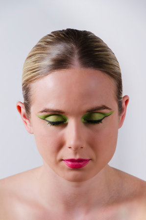 fashion glamour portrait of a blonde woman with heavy makeup and closed eyes vertically oriented