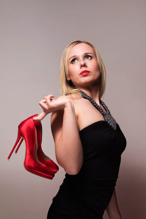 glamor shoot of a woman holding a pair of red heels in her handの写真素材