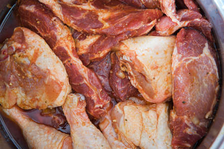 pieces mixed raw meat marinating in a steel potの写真素材