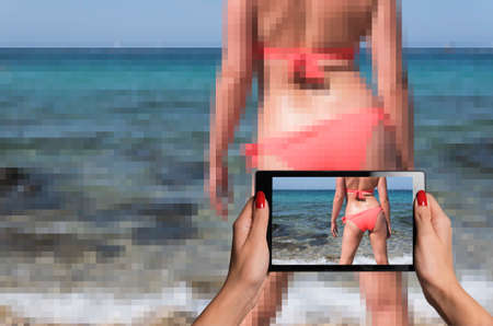 tablet taking photographs that look better than reality of a sexy woman wearing a bikini on a beachの写真素材