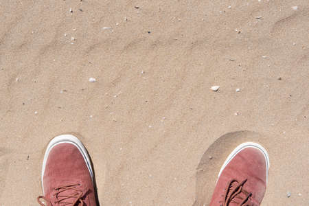 feet wearing sneakers standing on a sandの写真素材