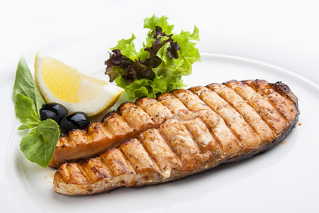 Salmon steak with lemon on a white plate.の写真素材