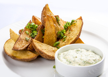 Pieces of baked potatoes with sauce. On a white plateの写真素材