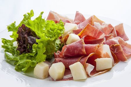 Prosciutto with melon on a white plateの写真素材