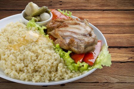 Millet porridge with chicken, pickles and vegetables. On a wooden backgroundの写真素材