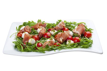 Caprese with prosciutto on a white plateの写真素材
