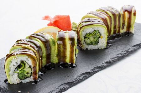 Sushi roll with avocado, cucumber, salad and seaweed. Vegetarian dish. On white background.の写真素材