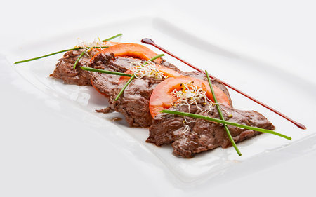 Beaten fried veal with tomatoes on white backgroundの写真素材