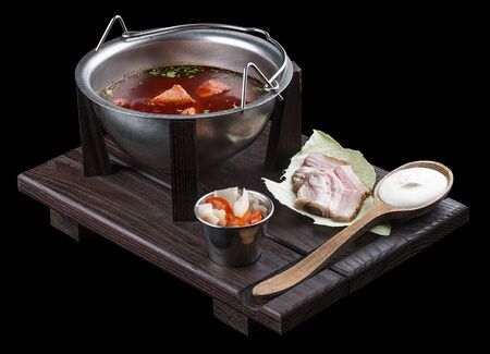 Ukrainian borscht with sour cream, bacon and spicy snacks on a wooden board. On dark backgroundの写真素材