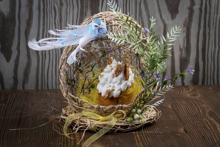 Decorative Easter basket with cake and colored eggs. On a wooden tableの写真素材