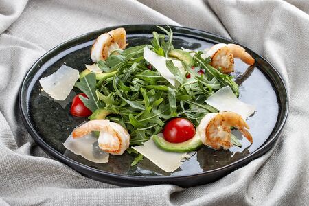 Salad with shrimp, cherry tomatoes, avocado and arugula on textile backgroundの写真素材