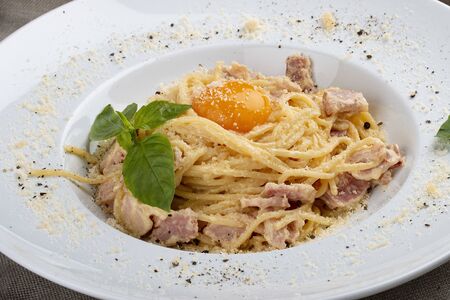 Spaghetti Carbonara on white plate on textile backgroundの写真素材