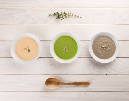 Set of diet cream soups on a light wooden background. Broccoli, pumpkin, mushrooms. Dietary and healthy food.の写真素材