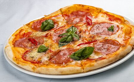 Delicious hot pizza with salami, cheese, tomatoes and various spices. On white backgroundの写真素材
