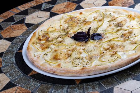 Pizza with pear and Gorgonzola cheese on a stone tableの写真素材
