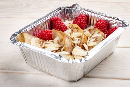 Porridge with pears and raspberries in containers on a white wooden background. Takeaway. Diet and healthy food.の写真素材
