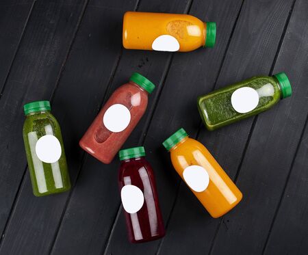 Fresh juices in bottles on dark wooden background. Detox drinks. Takeaway. Diet and healthy food.の写真素材