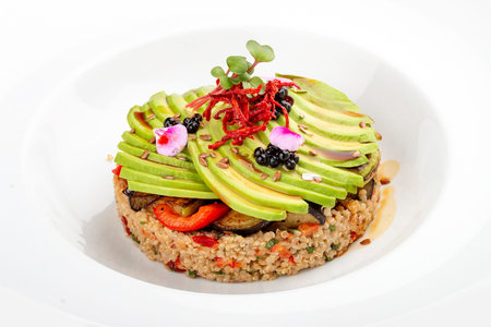 Salad with quinoa, avocado and roasted vegetables. On a colored wooden background. Vegetarian dish.