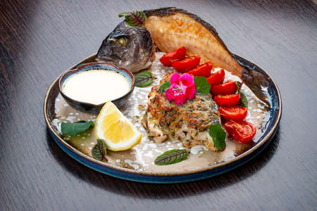 Dorado with parmesan cheese and greens. On a wooden backgroundの写真素材