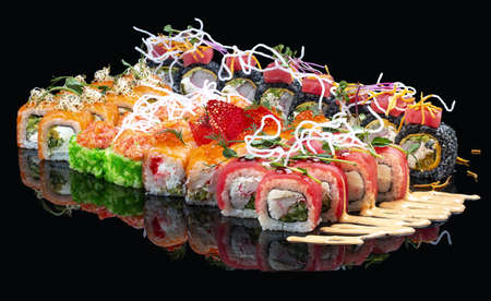 A set of assorted large sushi rolls on a glossy black backgroundの写真素材