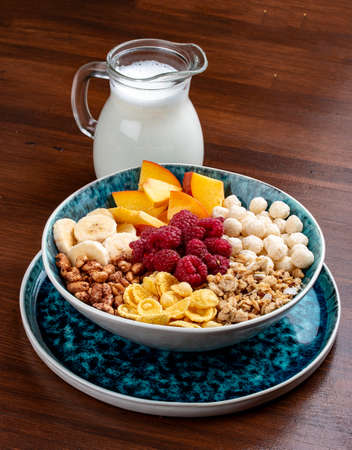 Muesli with banana, nuts, peach and raspberries. On a wooden background. Breakfastの写真素材