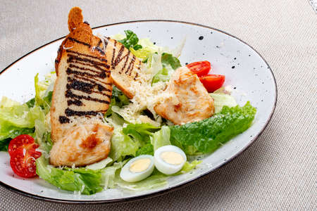 Caesar salad with chicken on a white decorative plate. A classic salad.の写真素材