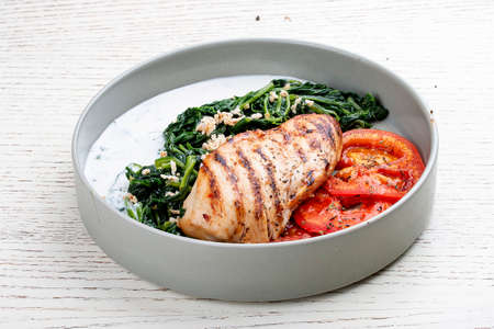 Fried chicken fillet with Greek dzadziki sauce and stewed spinach.の写真素材