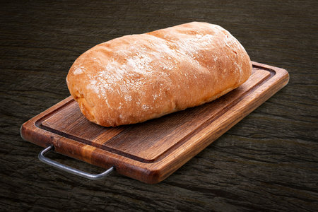 Wheat flour bread, handmade on a wooden board. On back background, isolated.
