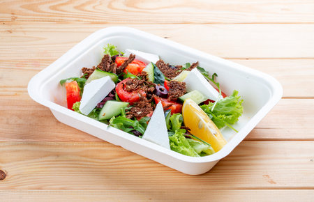 Greek salad with Tofu cheese. Healthy food. Takeaway food. On a wooden background.の写真素材