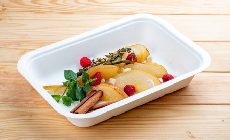Stewed pear in spices with nuts. Healthy food. Takeaway food. On a wooden background.