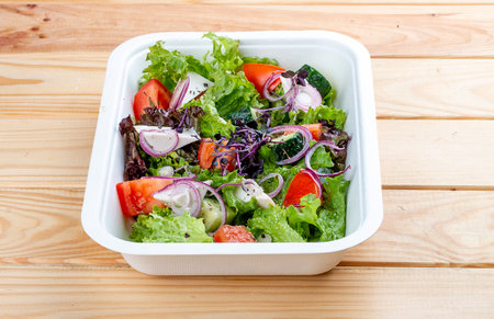Greek salad with feta cheese. Healthy diet.Takeaway food. On a wooden background.の写真素材