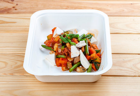 Sauteed vegetables. Healthy diet. Takeaway food. Ecological packaging. On a wooden background.の写真素材