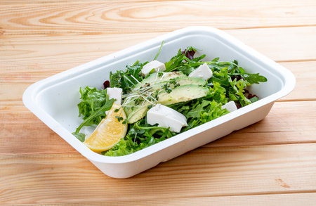 Salad mix (greens, avocado and tofu). Healthy food. Takeaway food. On a wooden background.の写真素材