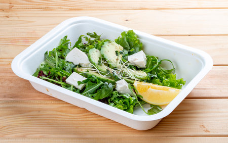 Salad mix (greens, avocado and tofu). Healthy food. Takeaway food. On a wooden background.の写真素材