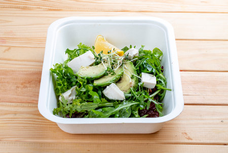 Salad mix (greens, avocado and tofu). Healthy food. Takeaway food. On a wooden background.の写真素材