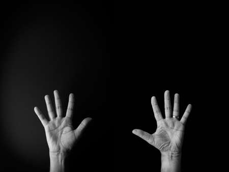 Dramatic black and white image of male hand demonstrating sign language number ten against black background with empty copy space for editorsの写真素材