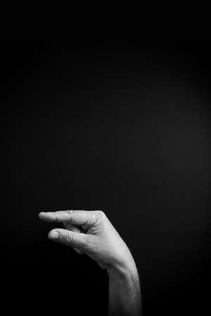 Dramatic B&W image of male hand demonstrating ASL American sign language letter F with empty copy space for editorsの写真素材