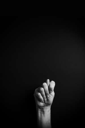 Dramatic B&W image of male hand demonstrating ASL American sign language letter T with empty copy space for editorsの写真素材