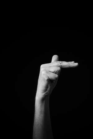 Dramatic B+W image of male hand fingerspelling CSL Chinese sign language letter SH isolated against dark backgroundの写真素材
