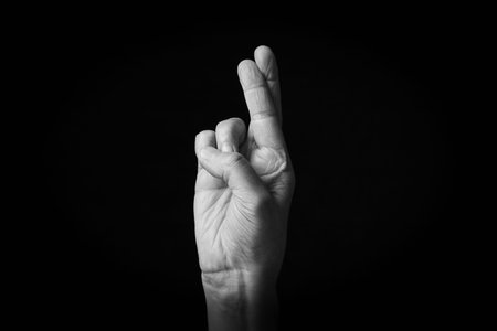Dramatic black and white image of Crossed Fingers emoji isolated on black background